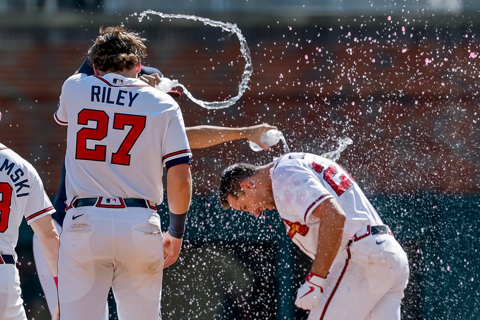 Atlanta Braves' Matt Olson, right, is doused by Austin Riley (27) and others after he hit the...