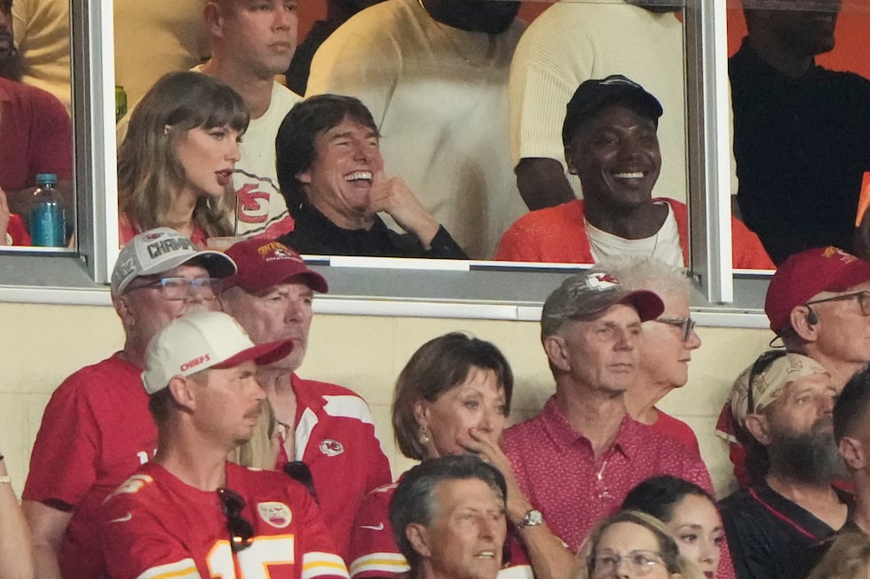 Taylor Swift, left, sits with Tom Cruise, center, while watching the first half of an NFL...